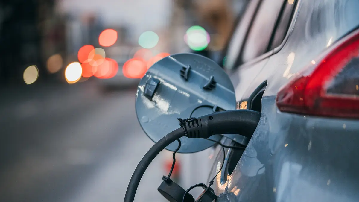 Conector de carga enchufado en un auto eléctrico en la calle