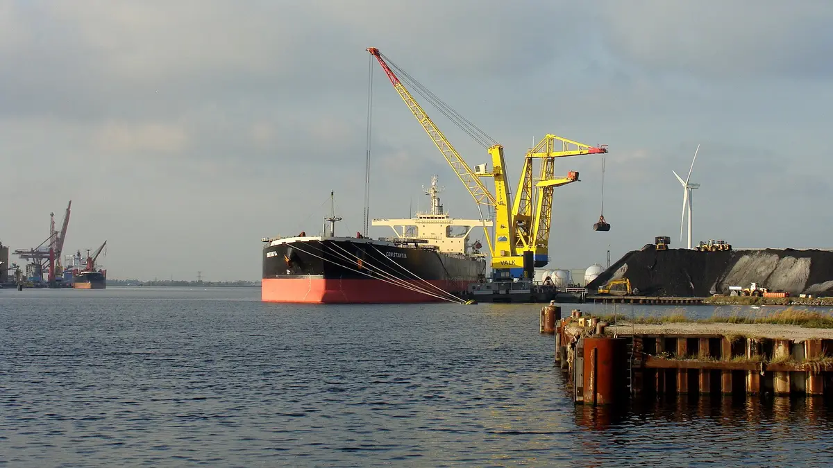 Guindaste descarregando carvão de um navio graneleiro para um pátio em um porto