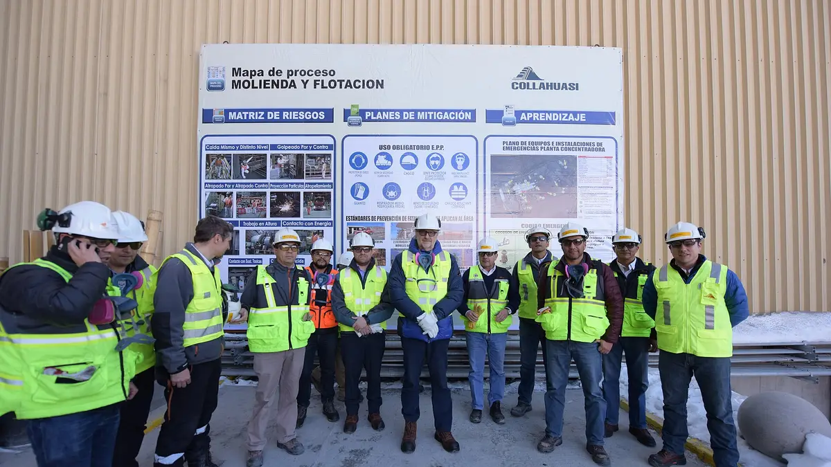 Workers in reflective vests and helmets in front of an information board at the Collahuasi mine
