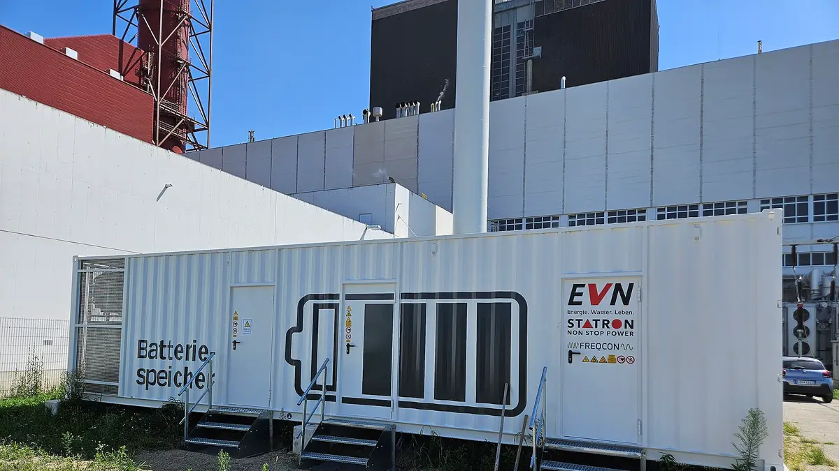Contenedor blanco de un sistema de almacenamiento en baterías junto a una central eléctrica