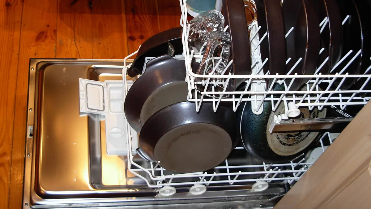 Open dishwasher with pots and plates in the lower rack