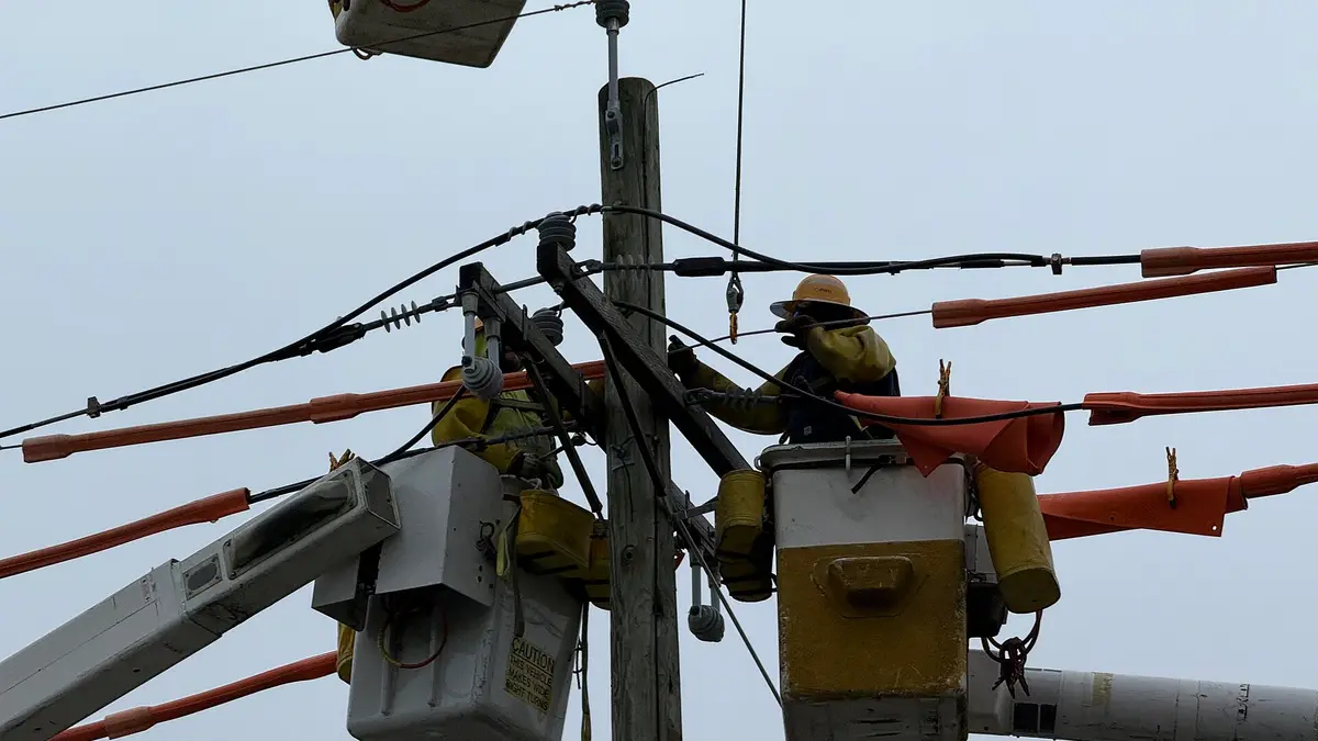 Trabajadores de una distribuidora eléctrica reparando un poste del tendido