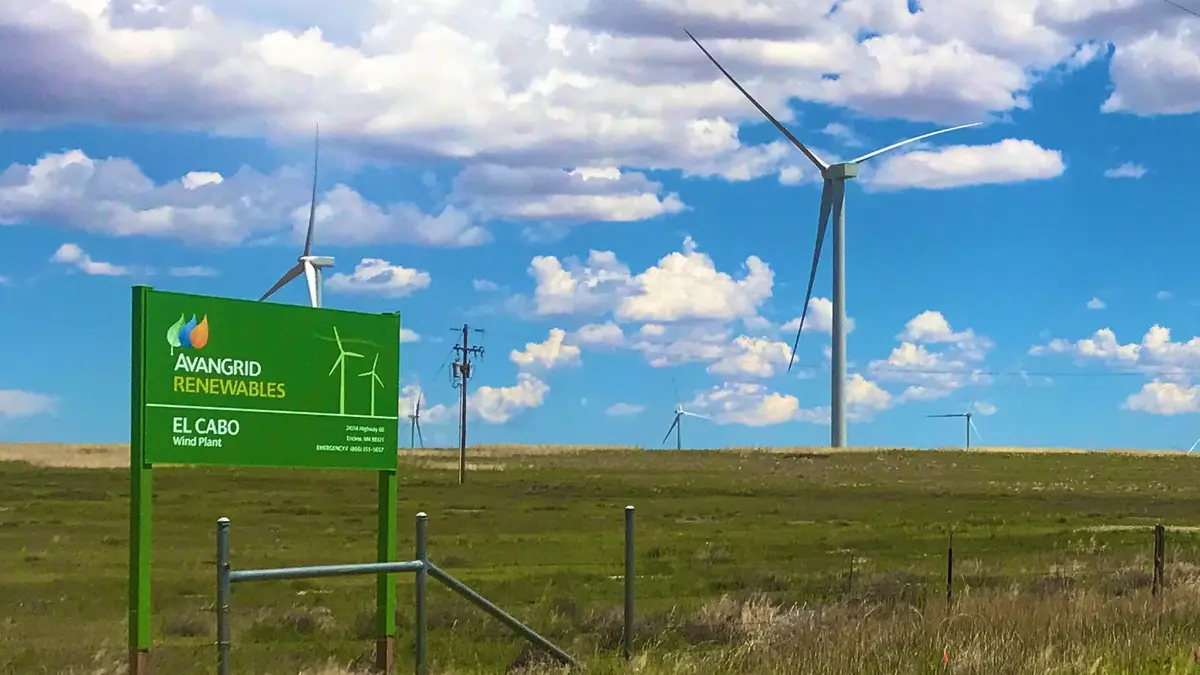 Aerogeneradores en una pradera de Nuevo México junto a un letrero del parque eólico El Cabo