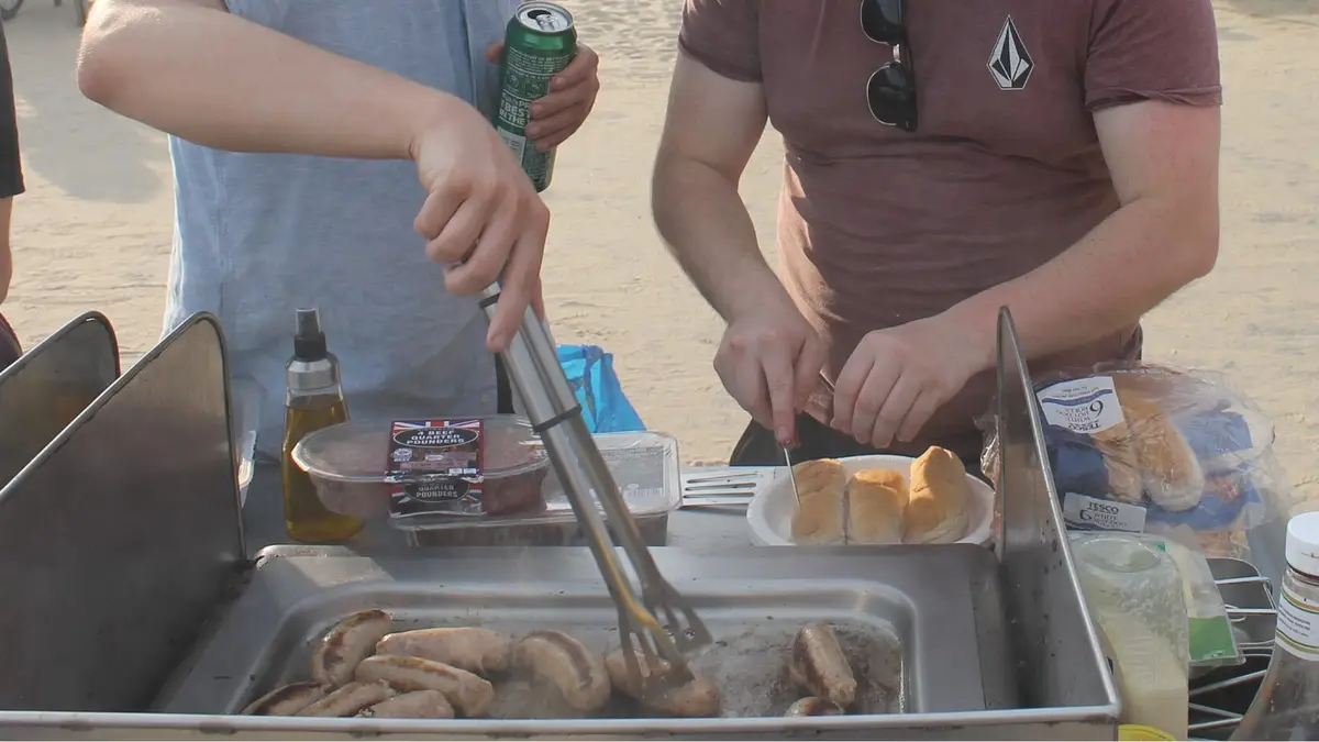 People cooking meat on an electric barbecue grill outdoors