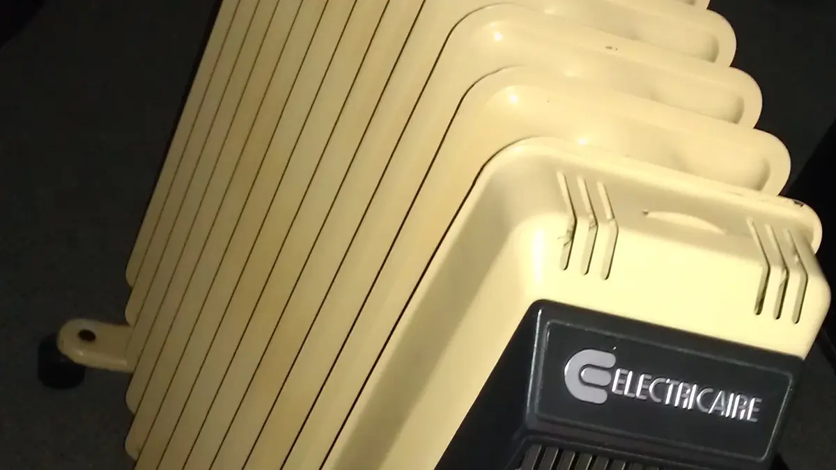 Radiador eléctrico de aceite de color crema enchufado en una habitación