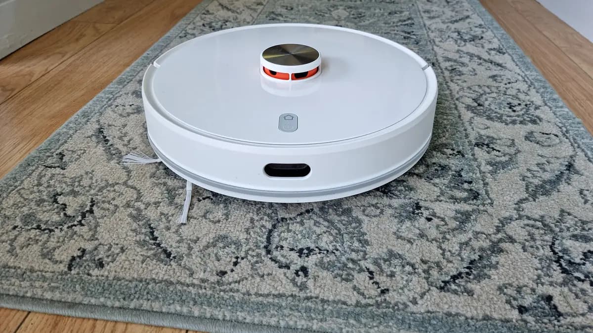Aspirador robô branco com sensor a laser sobre um tapete