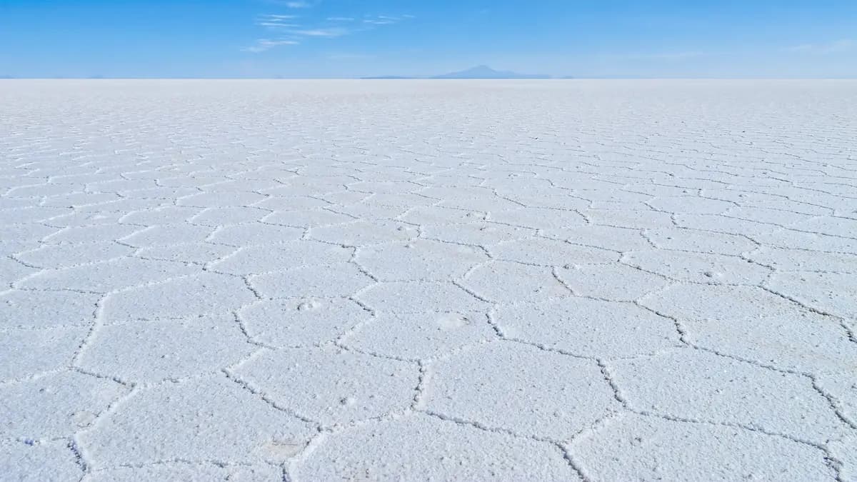 Superficie blanca y agrietada del Salar de Uyuni en Bolivia bajo un cielo azul