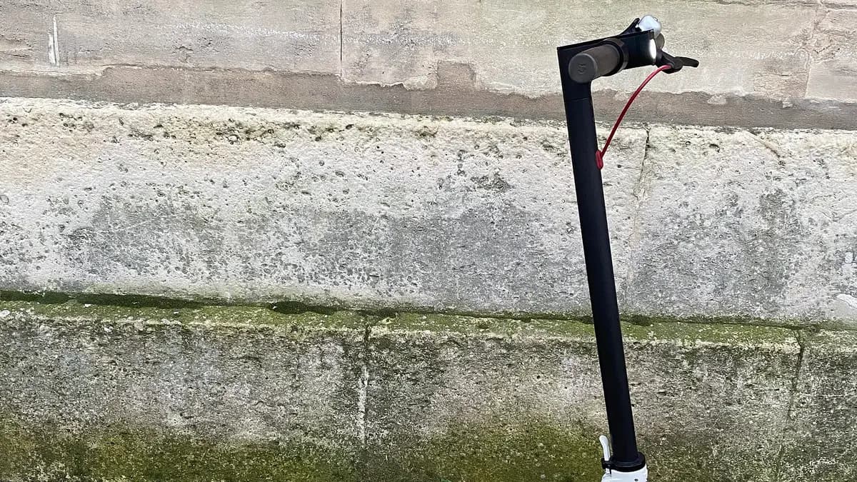 Scooter eléctrico Xiaomi M365 blanco apoyado contra un muro de piedra