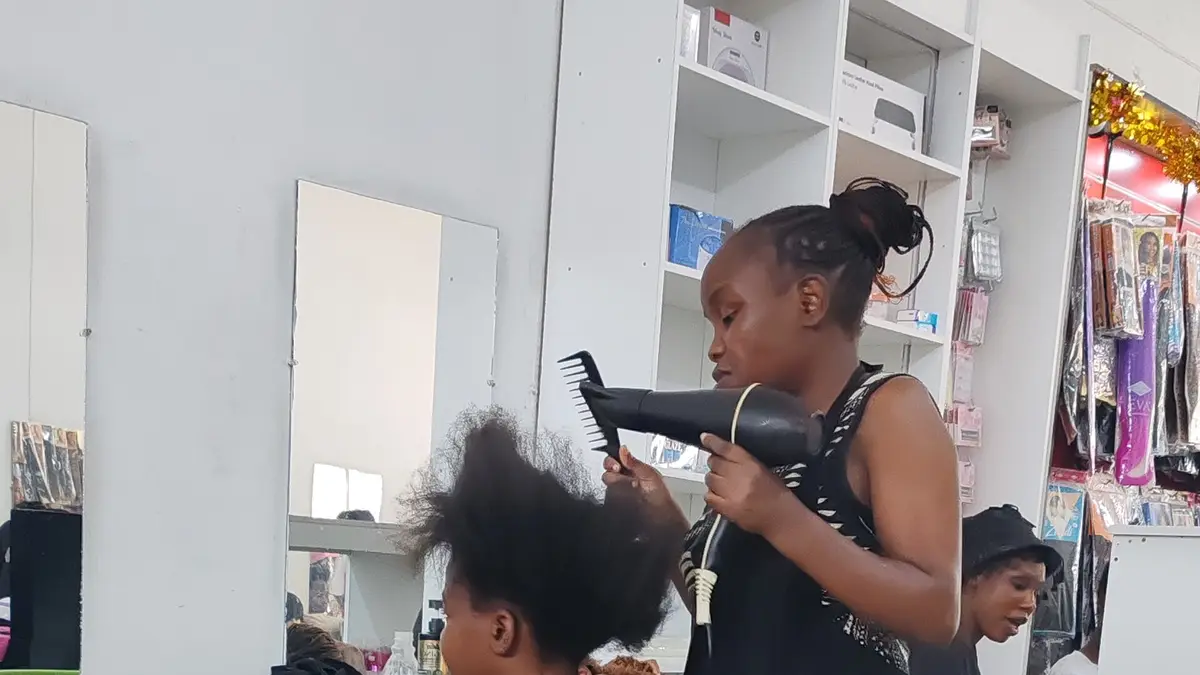 Cabeleireira secando o cabelo de uma cliente com um secador de mão