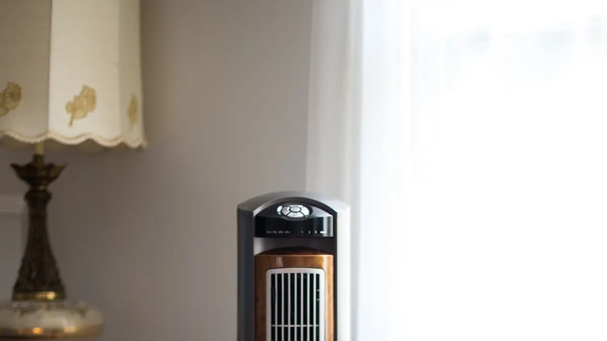 Ventilador de torre ao lado de um abajur em um quarto